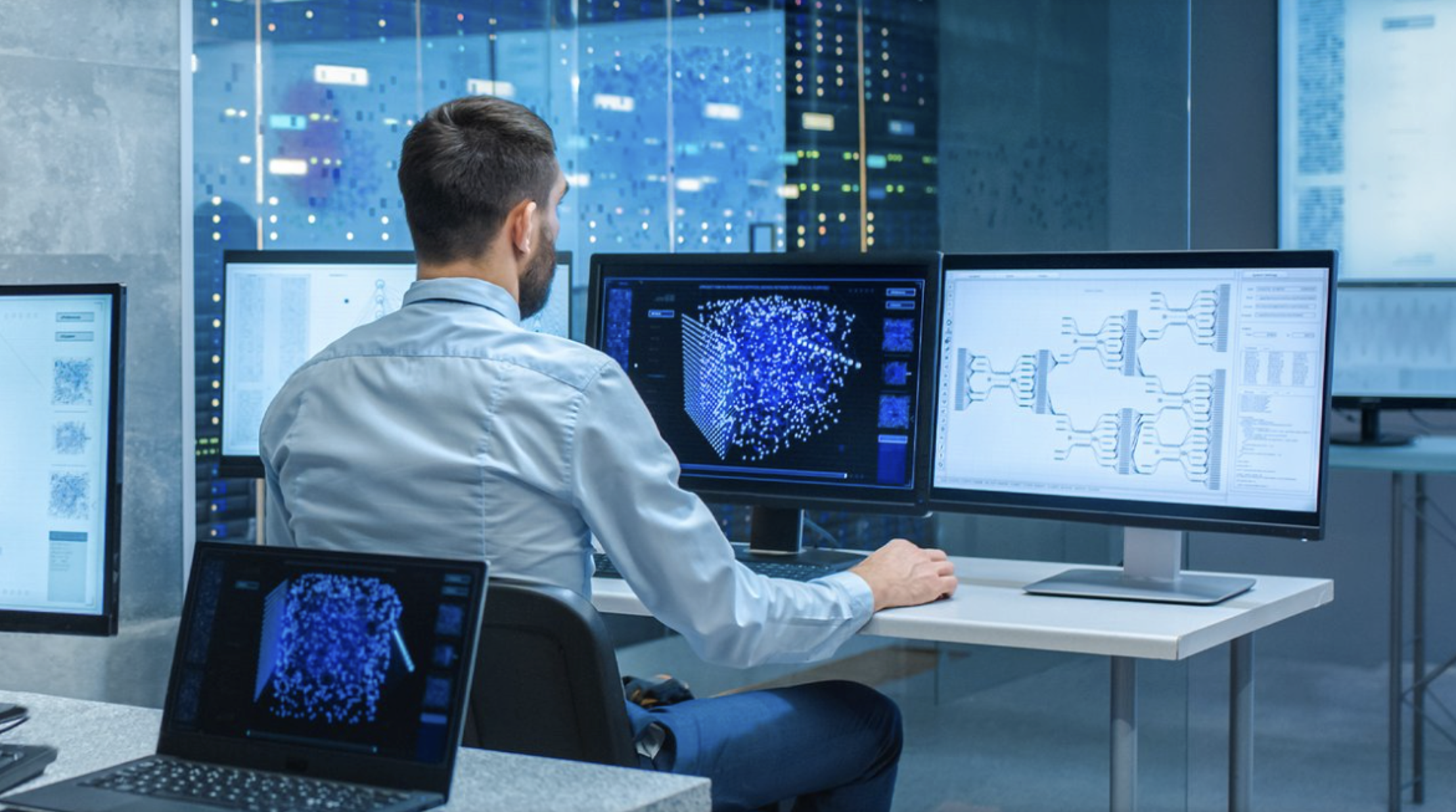 Mann sitzt in einem Datencenter vor Computermonitoren