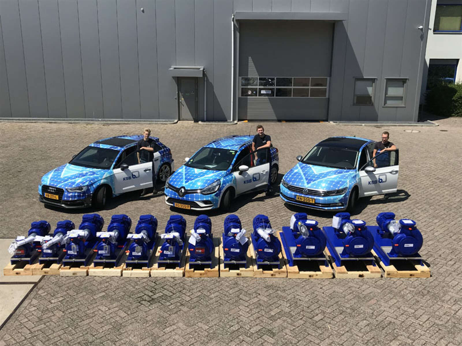 Jonge monteurs staan bij serviceauto's en bij pompen van KSB