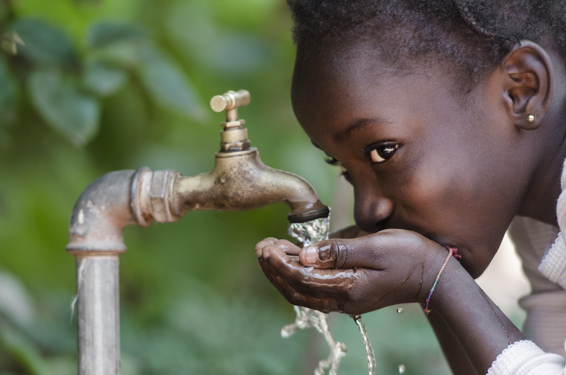 A girl drinking clear water from a tap