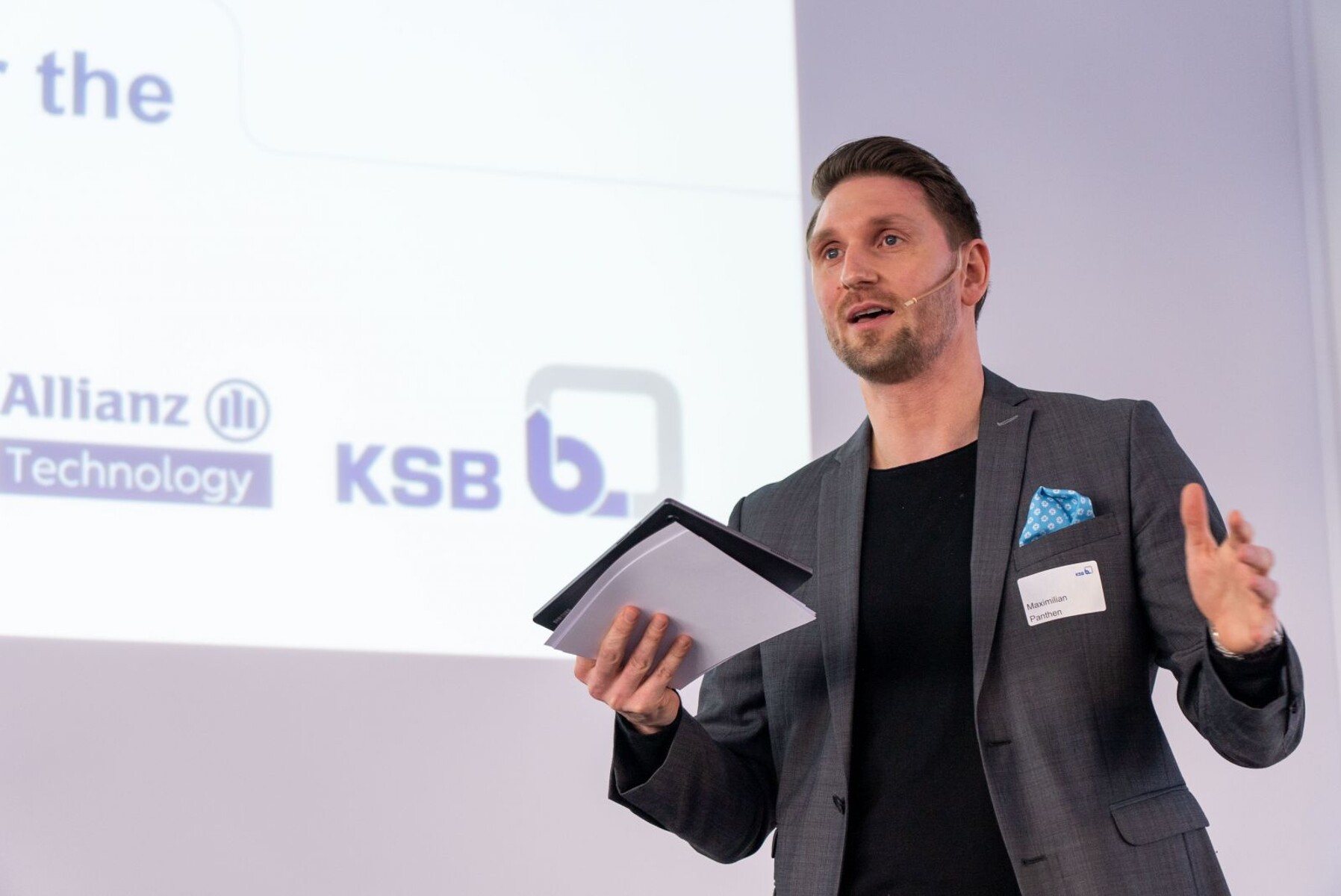 Maximilian Panthen als Redner bei einer Veranstaltung mit Mikrofon und Redenotizen in der Hand.
