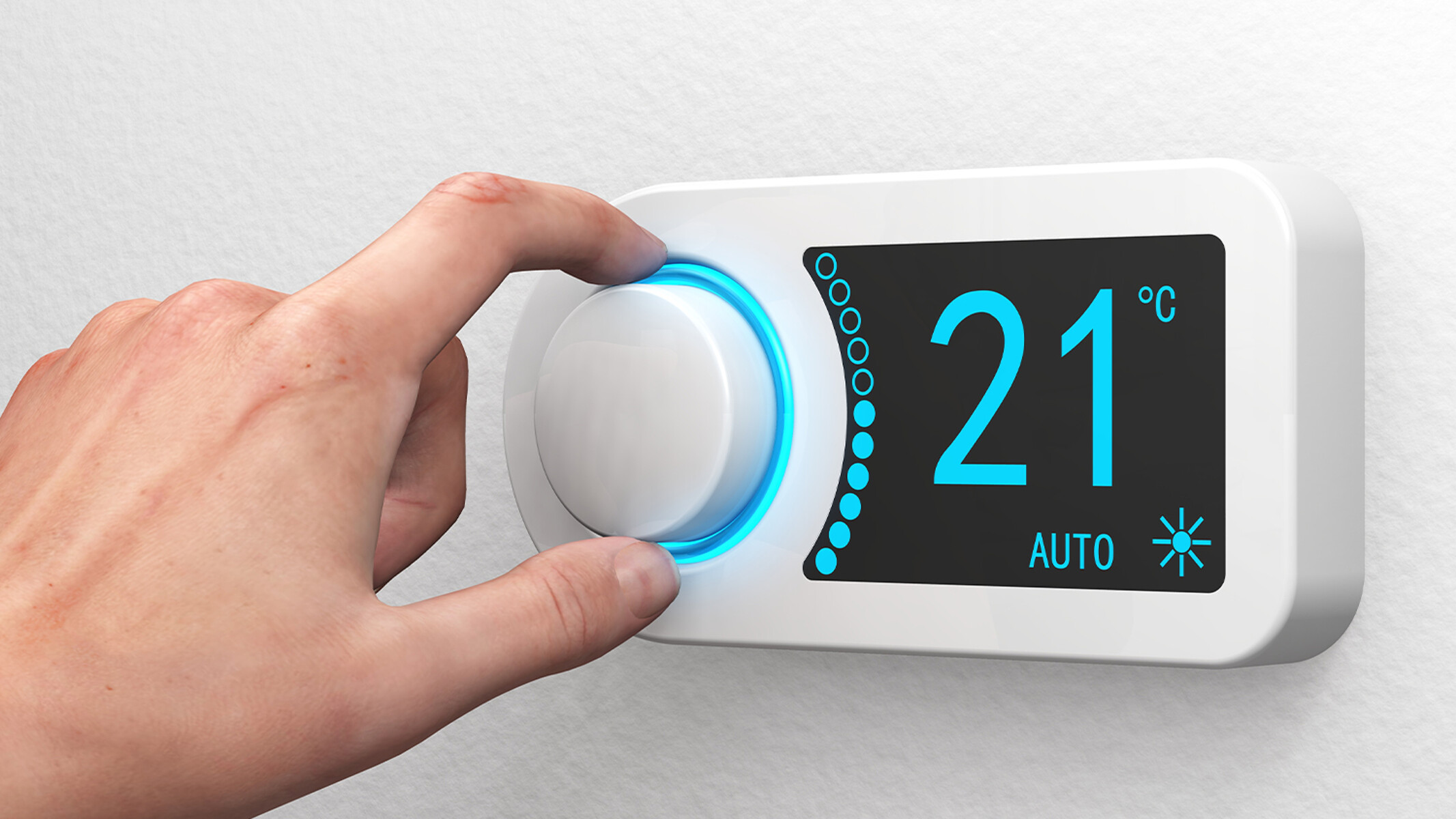 A hand controlling the temperature at a digital wall-mounted thermostat.