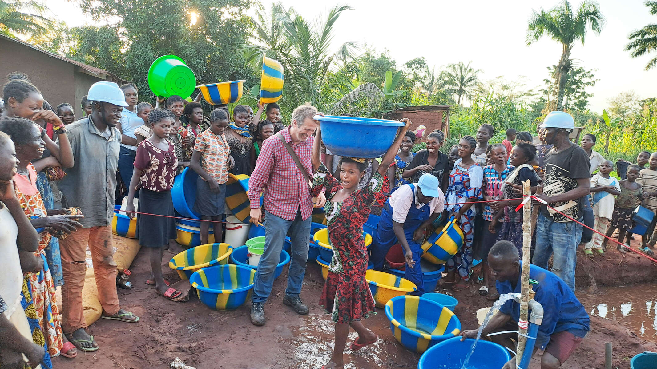 A crowd of people gathering in Tshikapa, Congo, around the outlet of a newly built well.