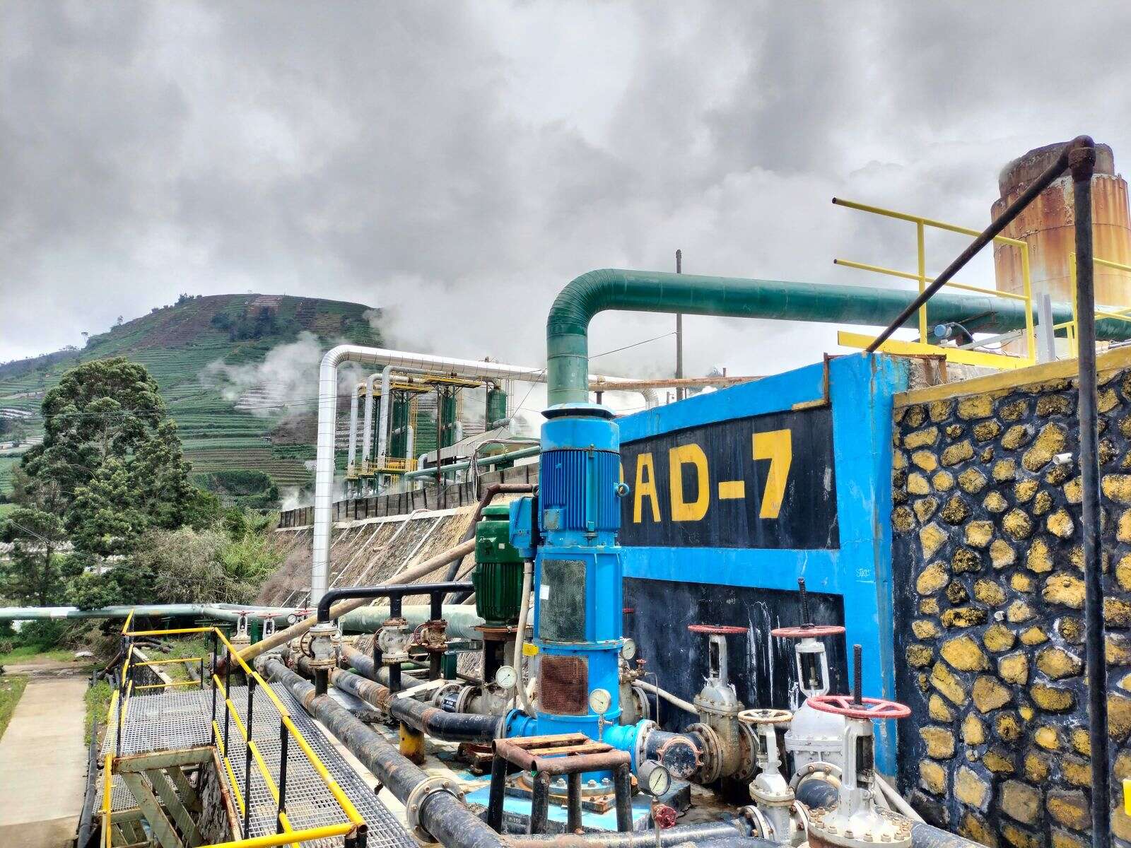 View of the power plant's pumps and pipelines, hilly background.