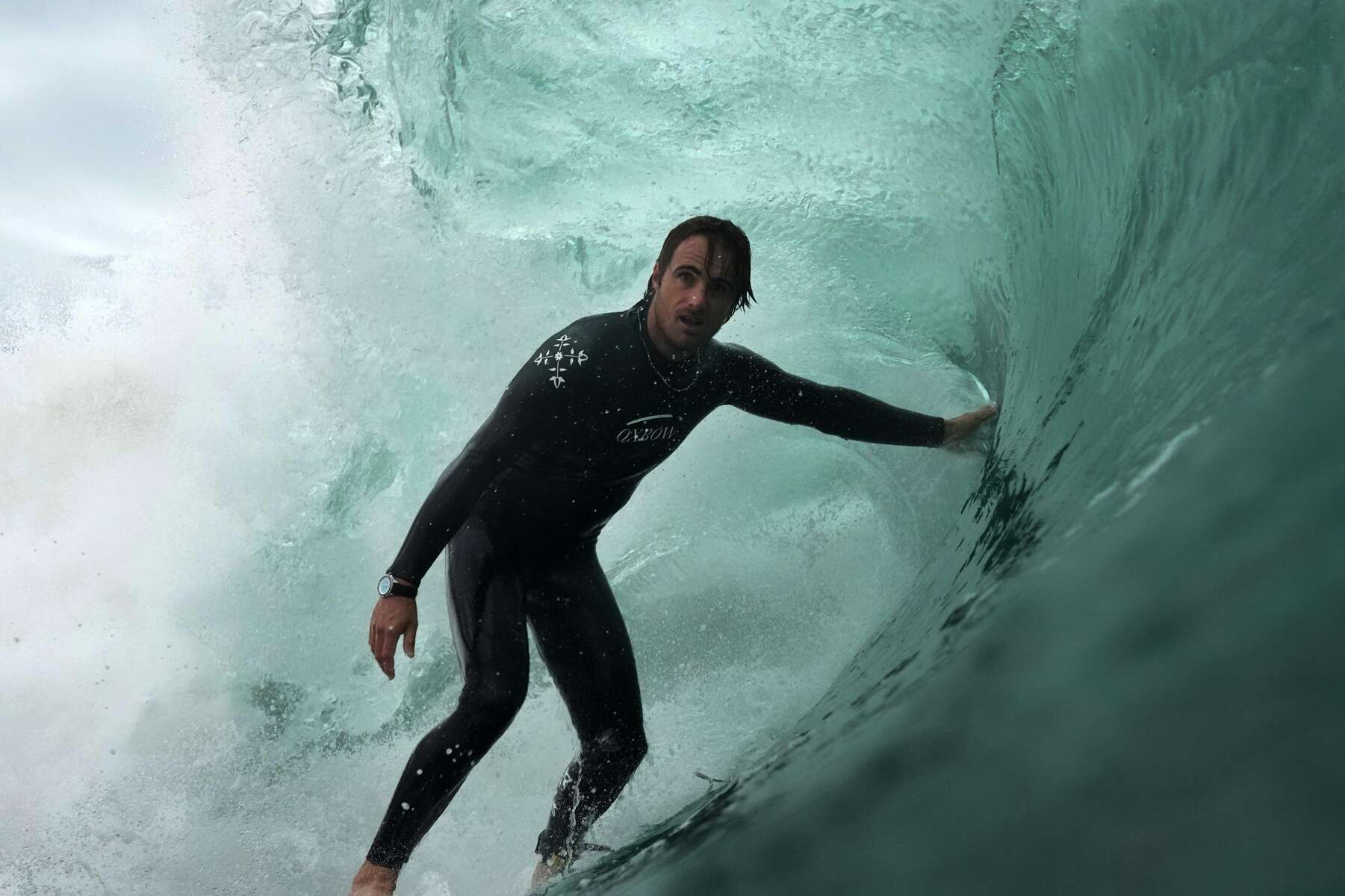 Natxo González on a surfboard inside the turquoise barrel of a wave