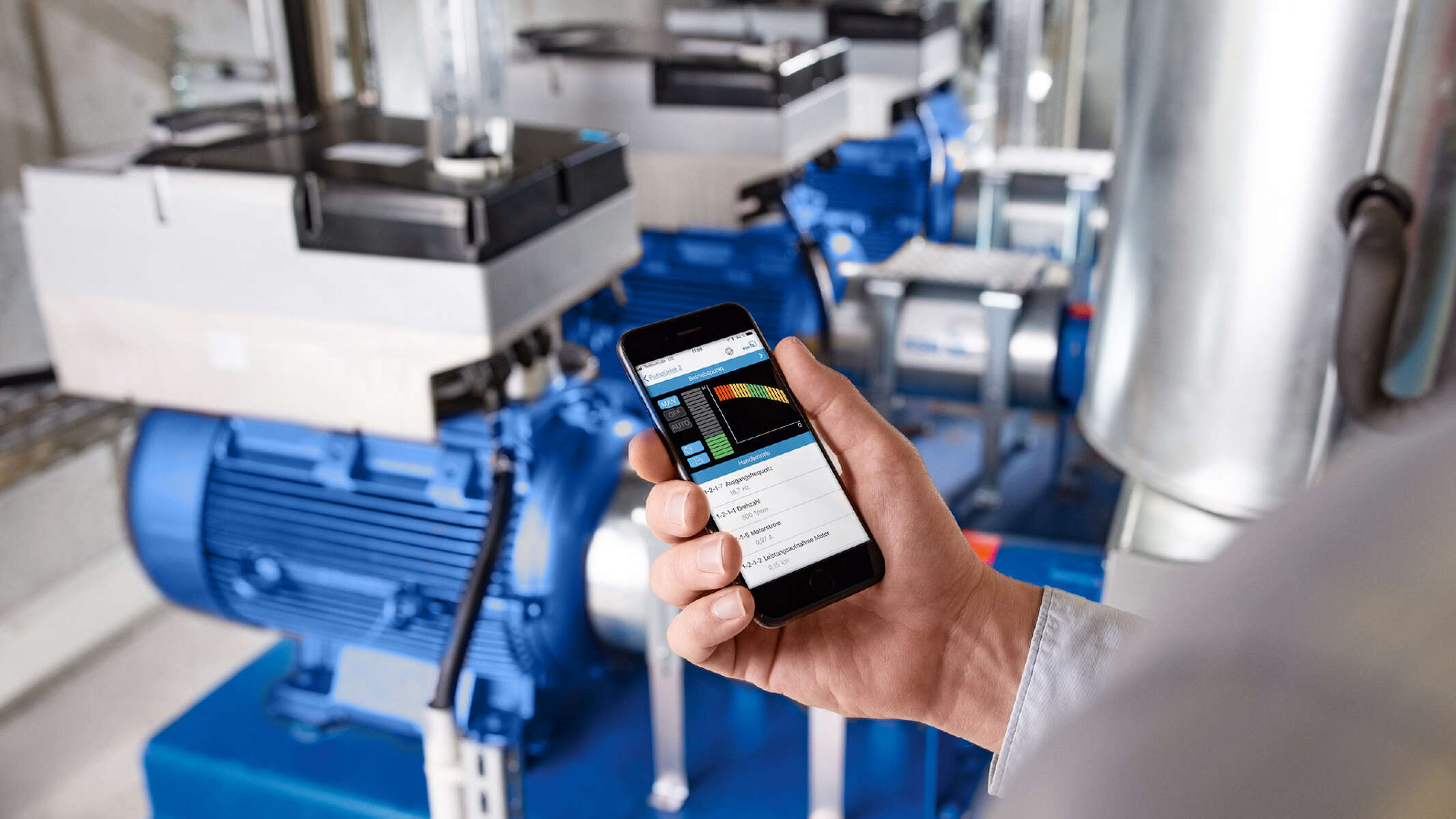 A person controls a pump via the KSB FlowManager app using their smartphone.