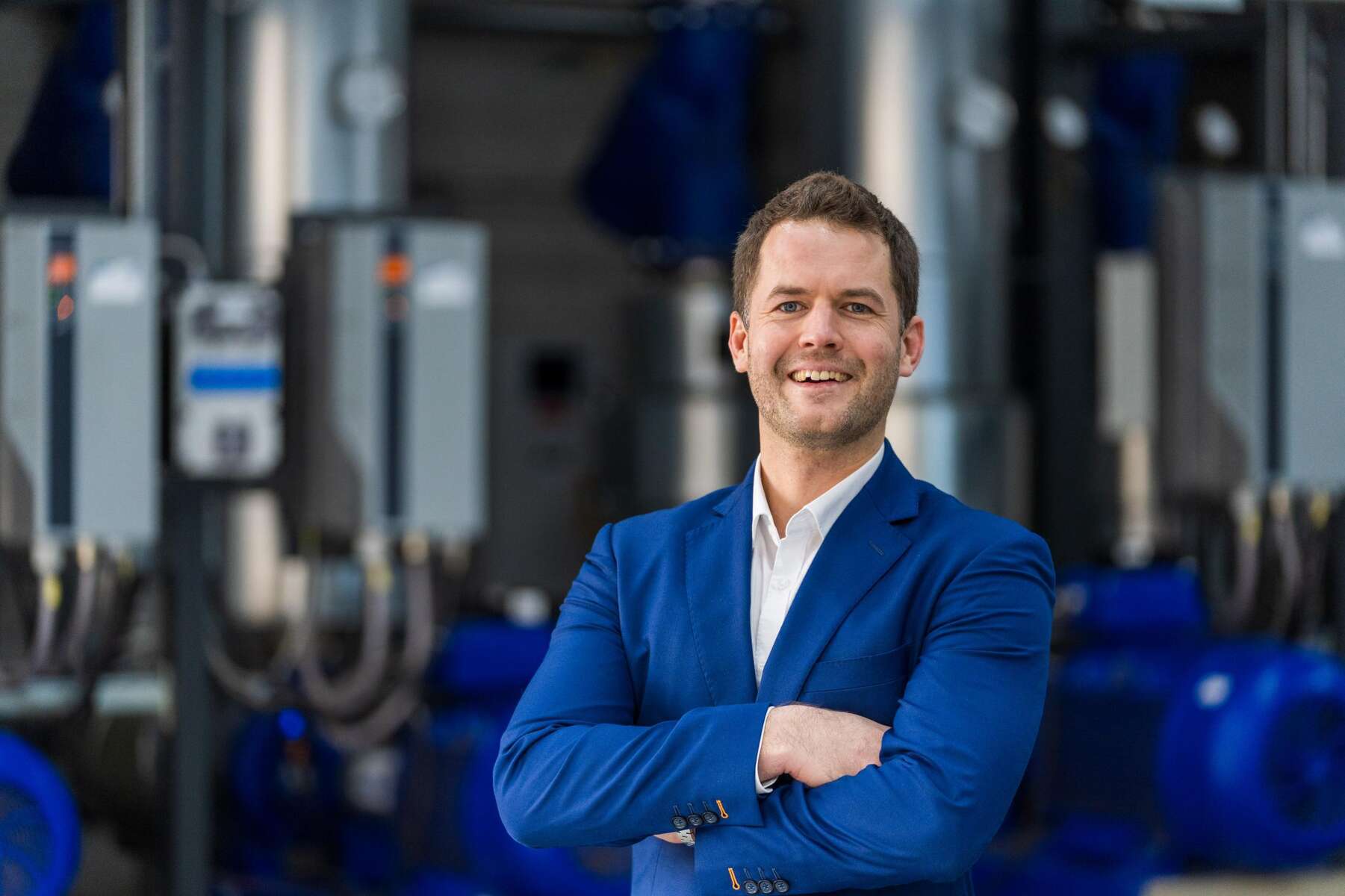 Jonas Bialk in a blue jacket in front of a modern heating system