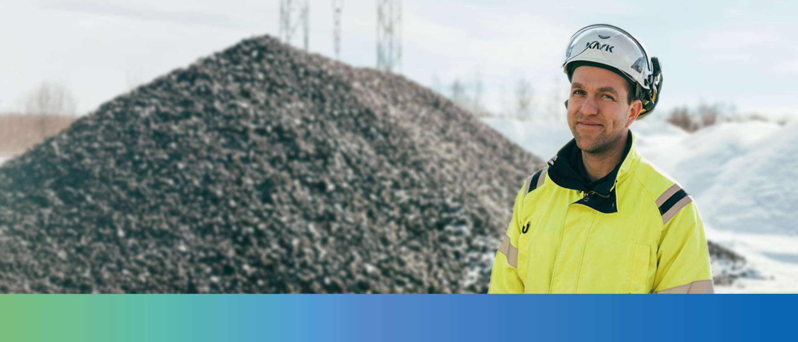 A KSB employee in work clothes in front of the interior of a factory building.