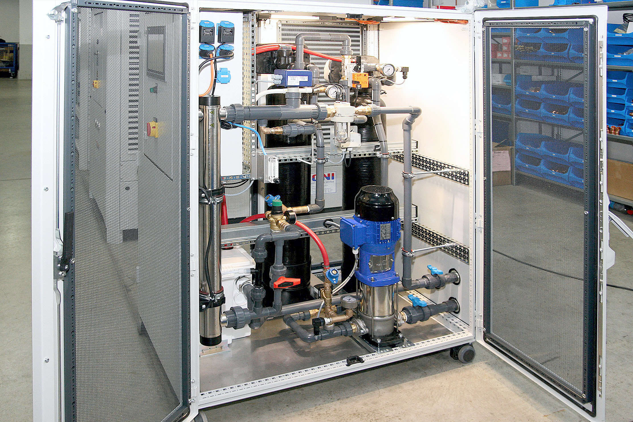 <p>The ONI-AquaClean filter flushing station in its working environment</p> An opened ONI-AquaClean filter flushing station with piping and KSB pump