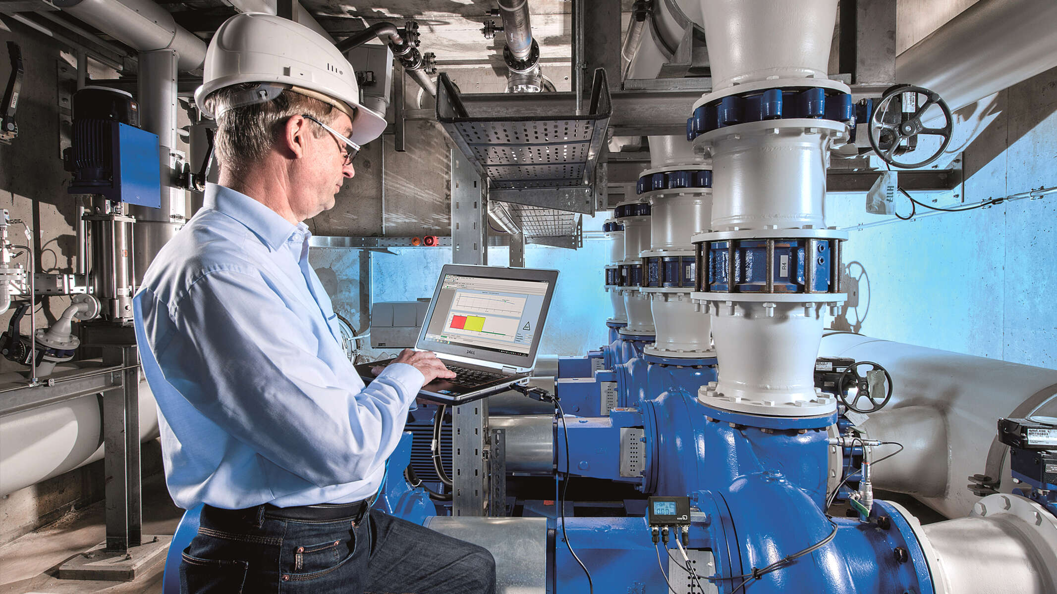 Ingénieur avec ordinateur portable devant une pompe