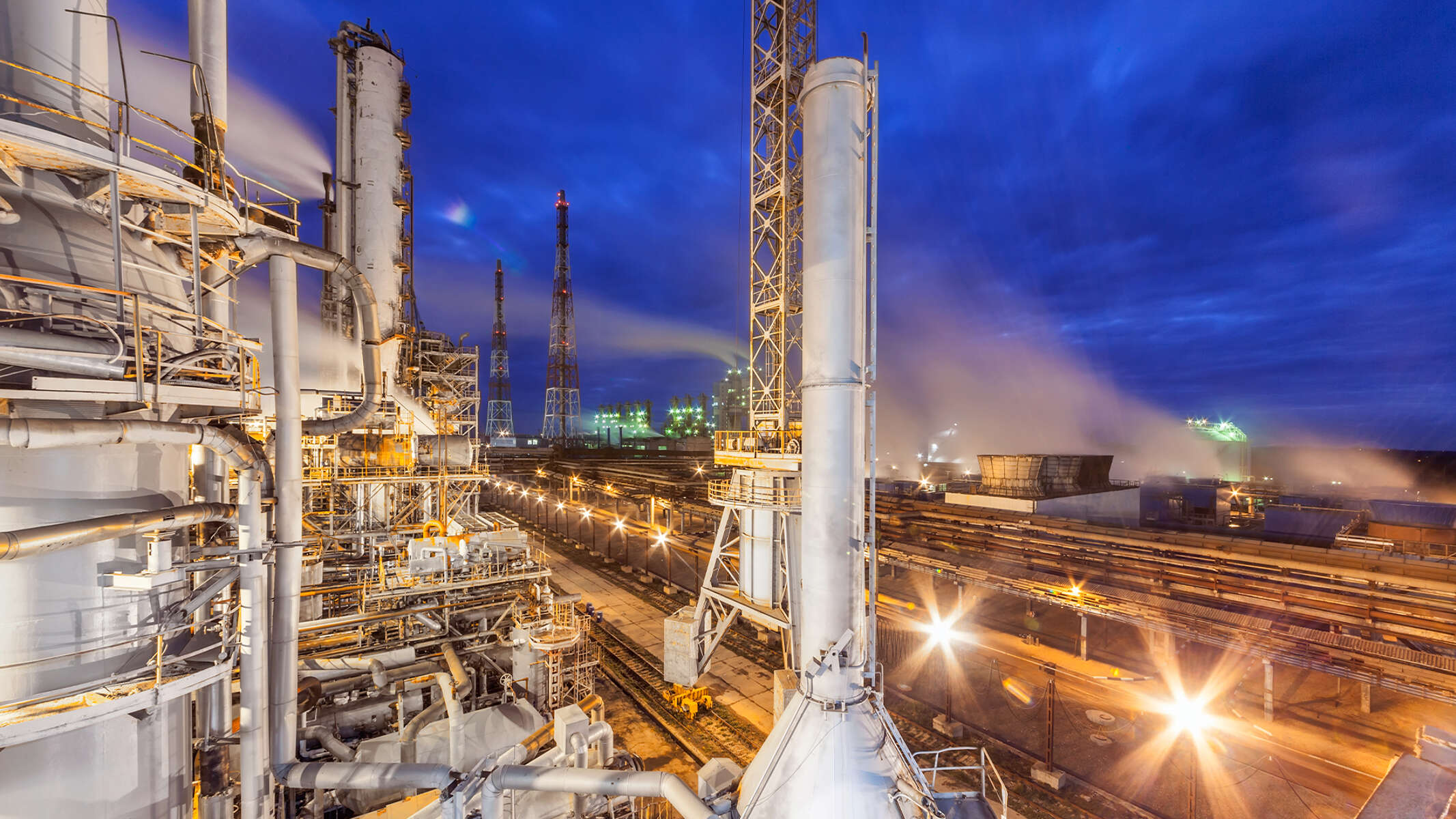 Industrial chemicals plant overlooking a railroad by night