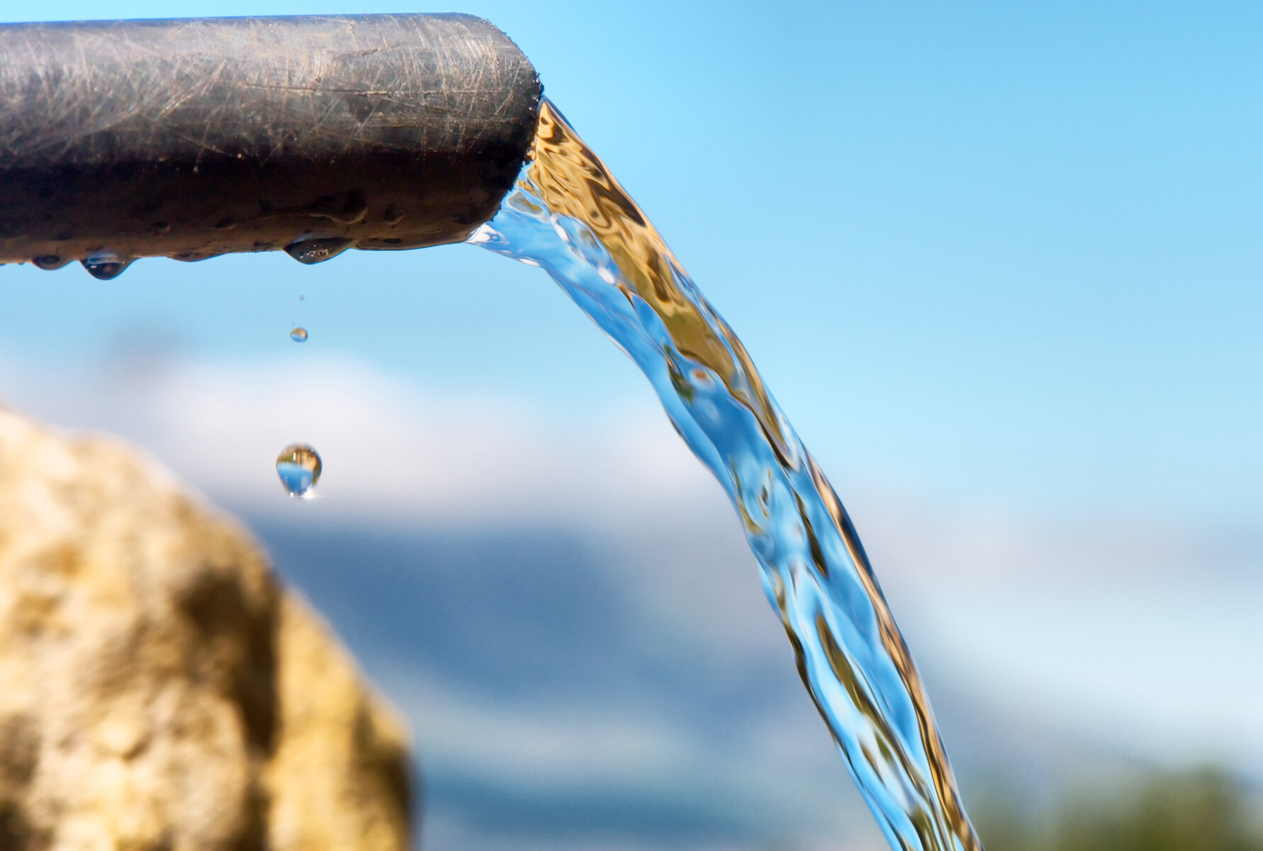 Água limpa flui através de um tubo para dentro de um reservatório de água.