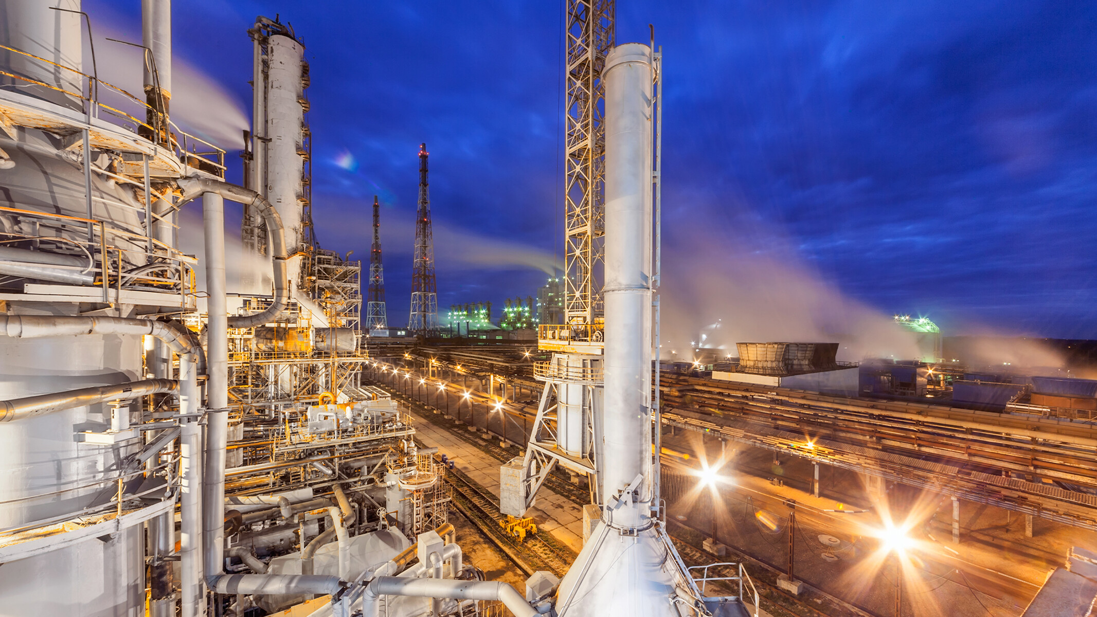 Industrial chemicals plant overlooking a railroad by night