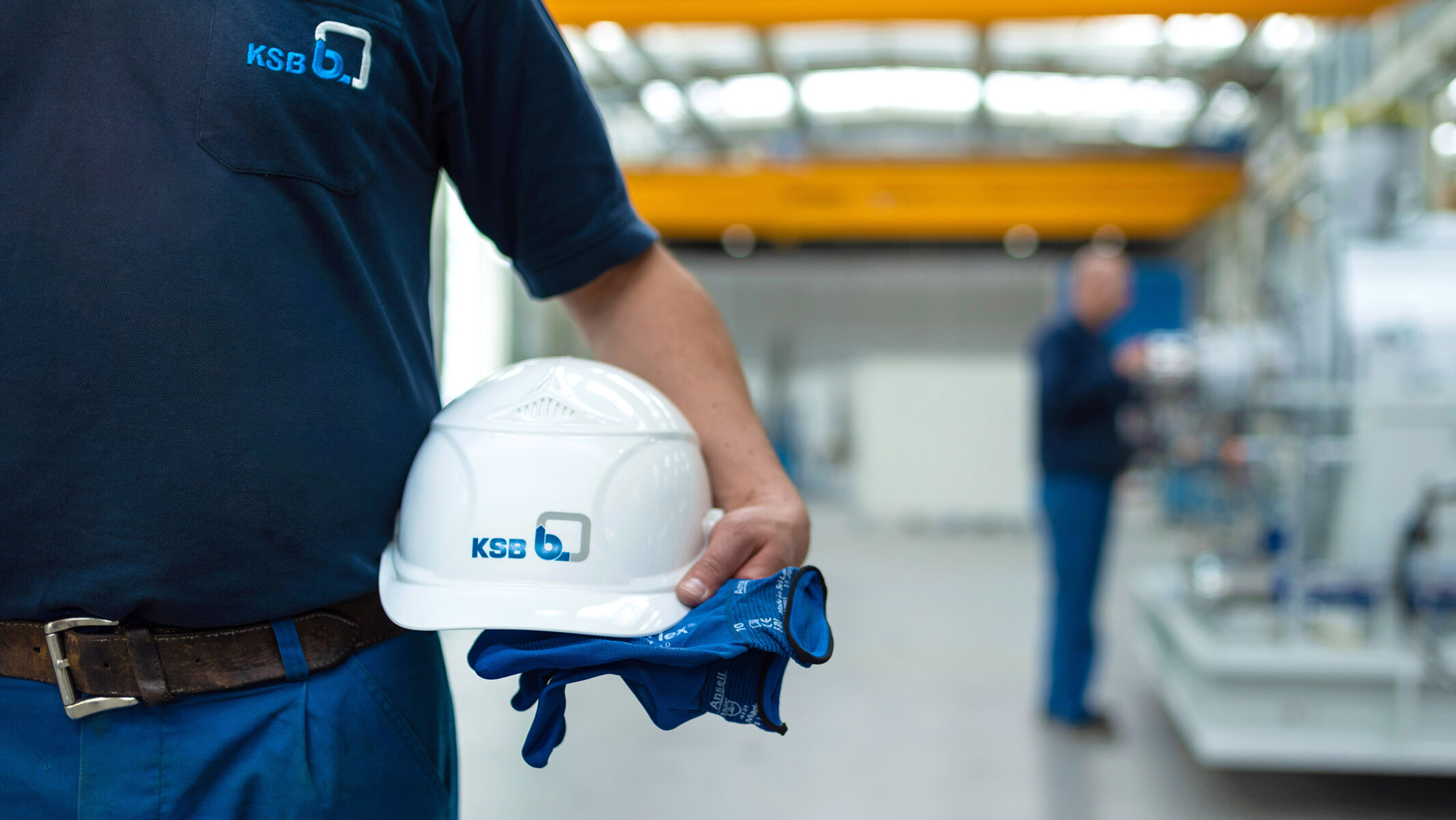 KSB Mitarbeiter hält einen Helm und Handschuhe