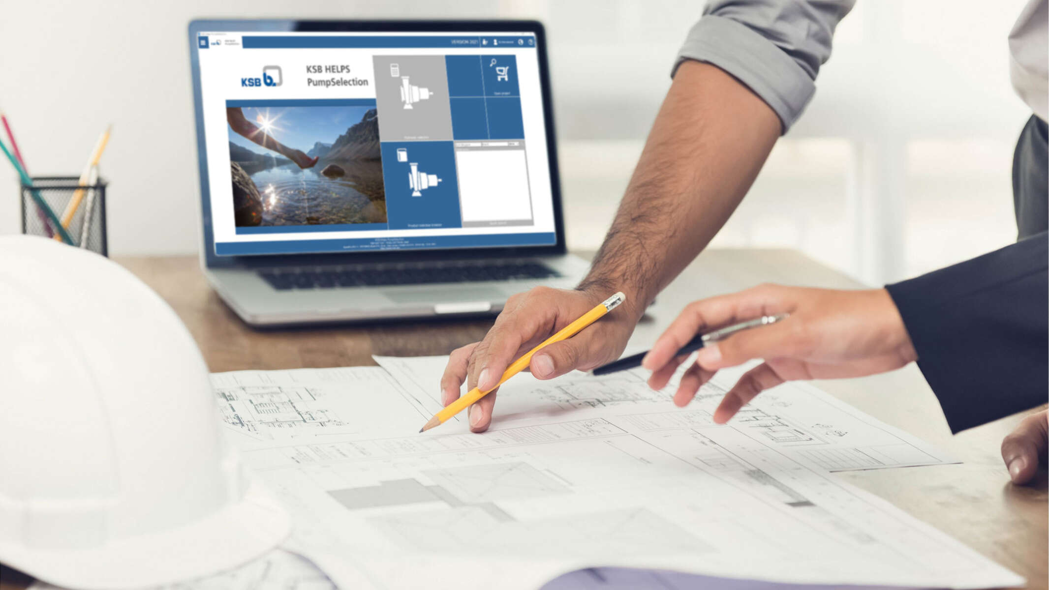 Consultants are leaning over plans; in the background a laptop can be seen with the KSB HELPS PumpSelection software