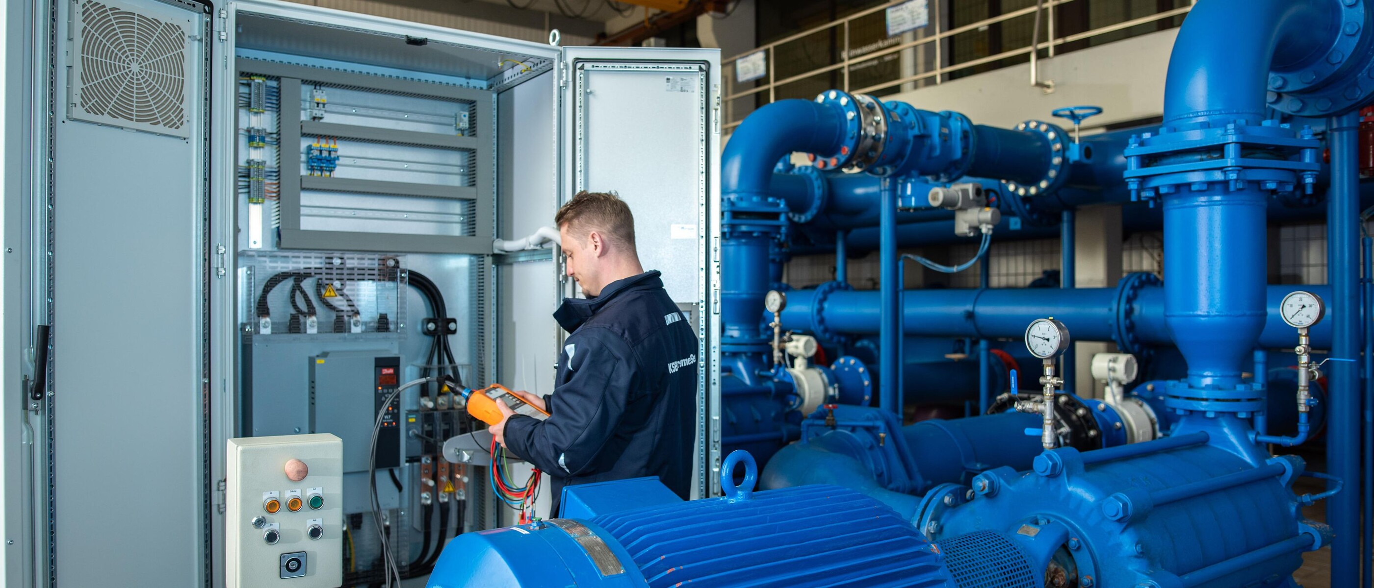 Comprehensive system analysis of a pump system for increasing efficiency: Engineer with analysis device at a control cabinet