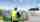 A man, wearing a hard hat and a yellow hi-vis vest, looking at hydrogen tanks, wind turbines and solar panels